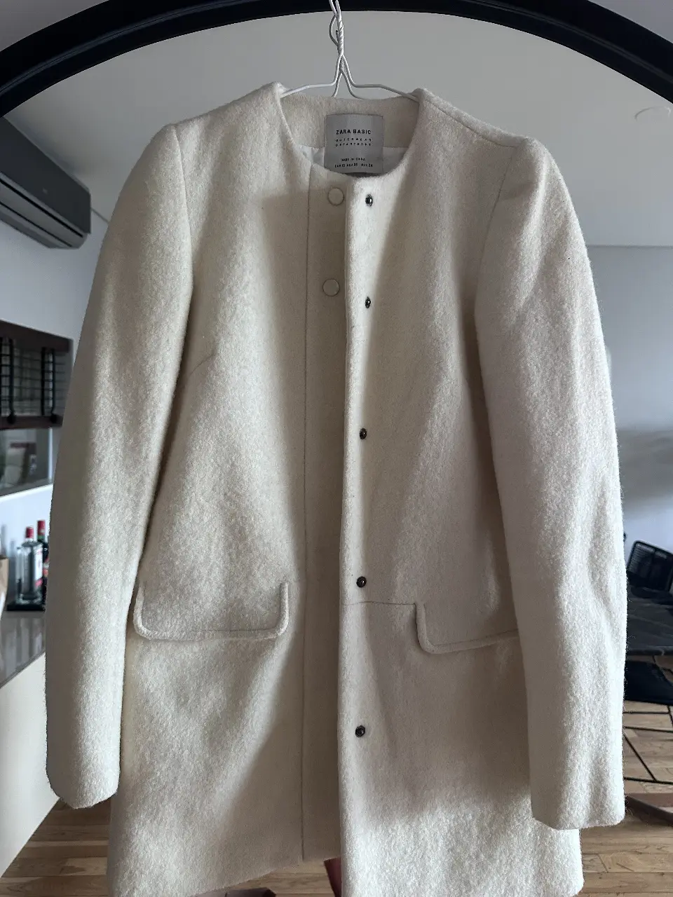 Sobretodo blanco de la marca Zara Basic, con cuello redondo y botones. Ideal para un look elegante y abrigado.