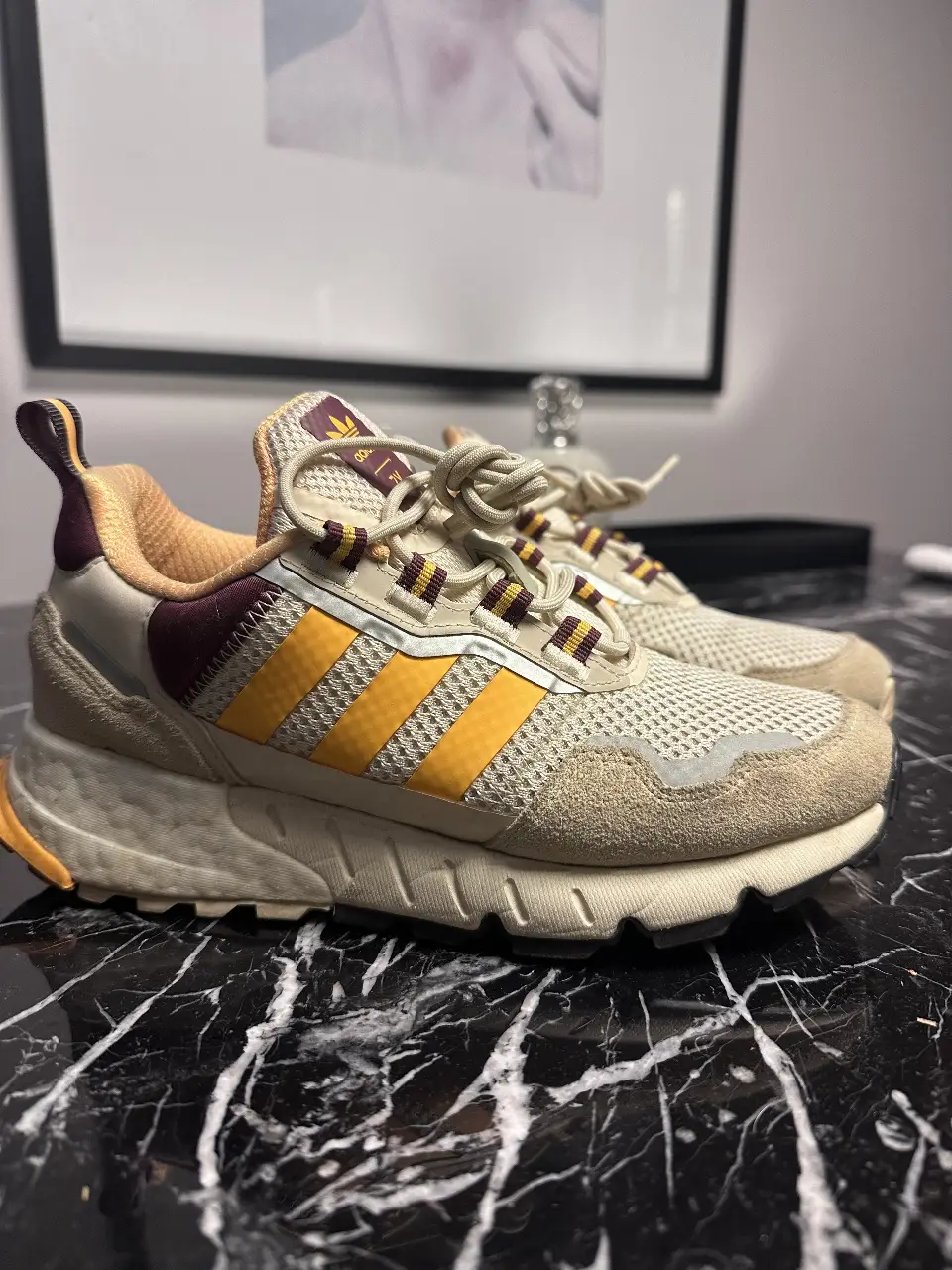 Zapatillas Adidas ZX 2K Boost, color crudo con detalles en amarillo y bordó. Ideales para un look deportivo y urbano.
