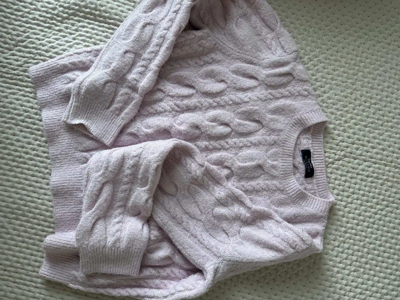 Sweater de punto grueso color rosa claro, con diseño de trenzas. Ideal para un look casual y abrigado.