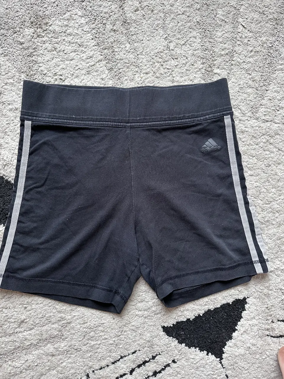 Short deportivo Adidas negro con detalles en gris. Ideal para entrenar o usar en el día a día. Talle M.