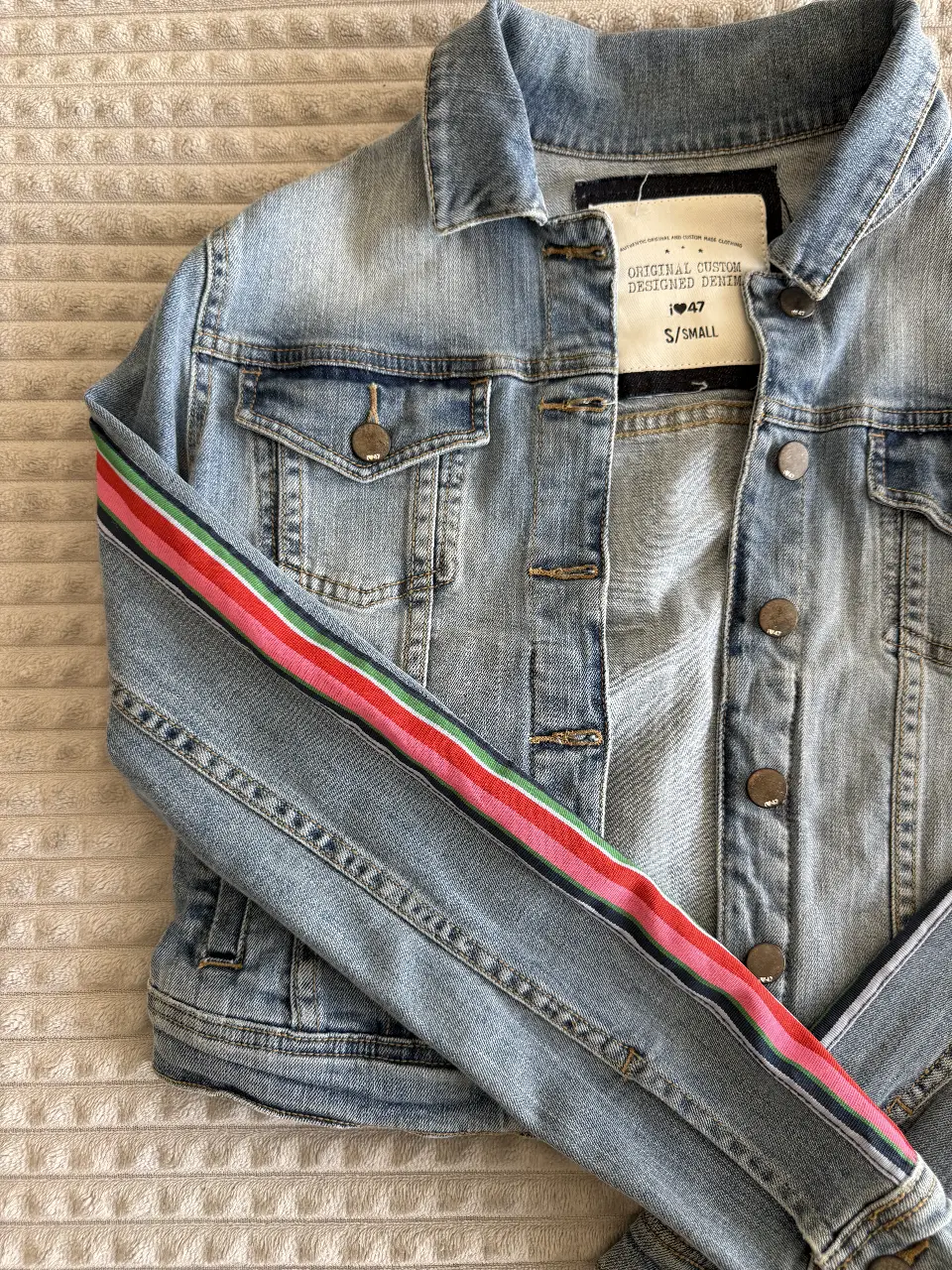 Campera de jean azul claro con detalles de rayas en las mangas. Talle S/Small. Ideal para un look casual y moderno.