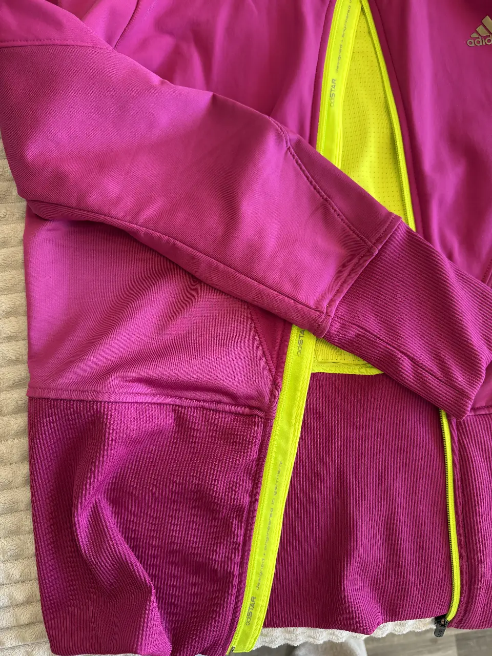 Buzo deportivo Adidas con cierre, capucha y detalles en amarillo. Ideal para actividades al aire libre.