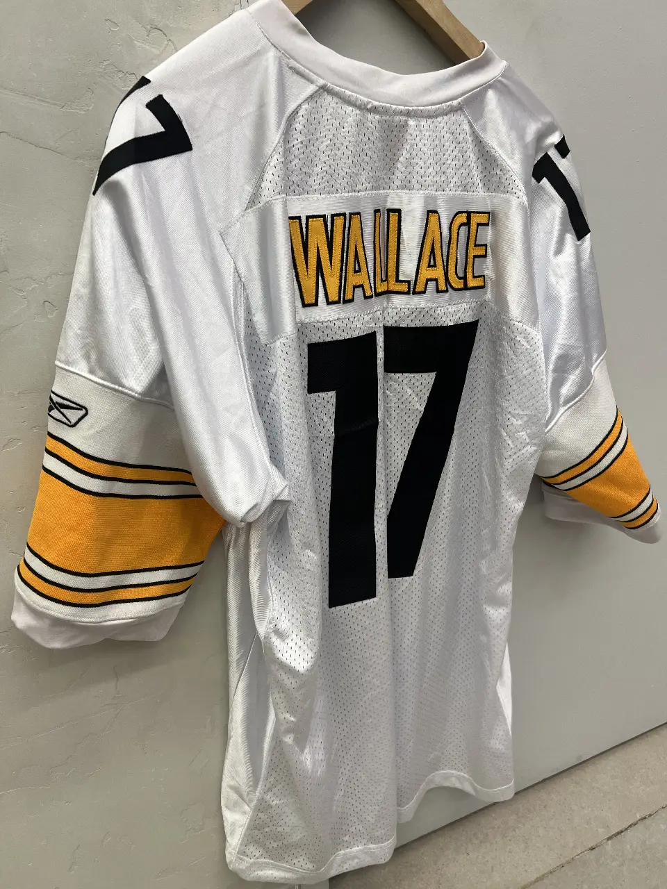 Camiseta de fútbol americano de la NFL de los Steelers, con el número 17 y el nombre Wallace. Blanca con detalles en amarillo y negro. Ideal para fanáticos y coleccionistas.