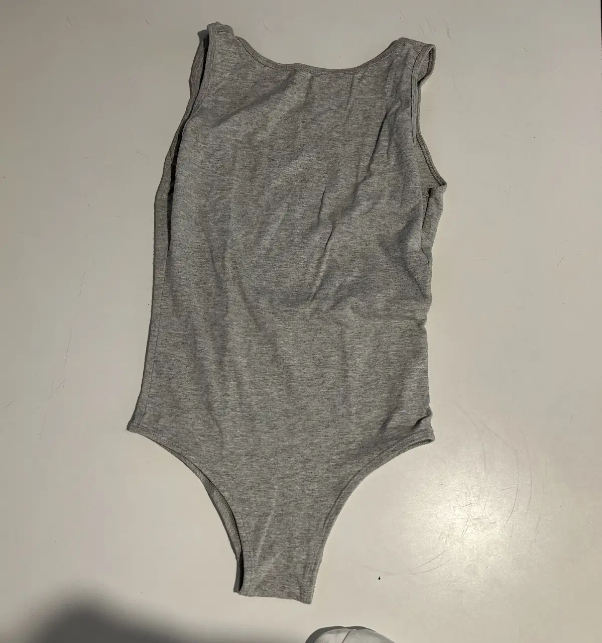 Body de mujer de algodón gris, escote redondo y corte cavado. Ideal para un look casual y cómodo.