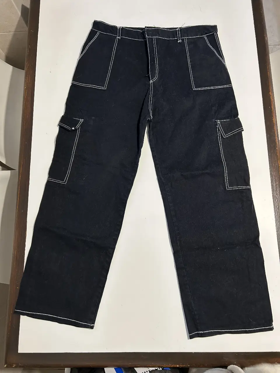Pantalón cargo negro con costuras blancas. Tiro medio, con bolsillos laterales y traseros. Ideal para un look casual y urbano. Talle M/L