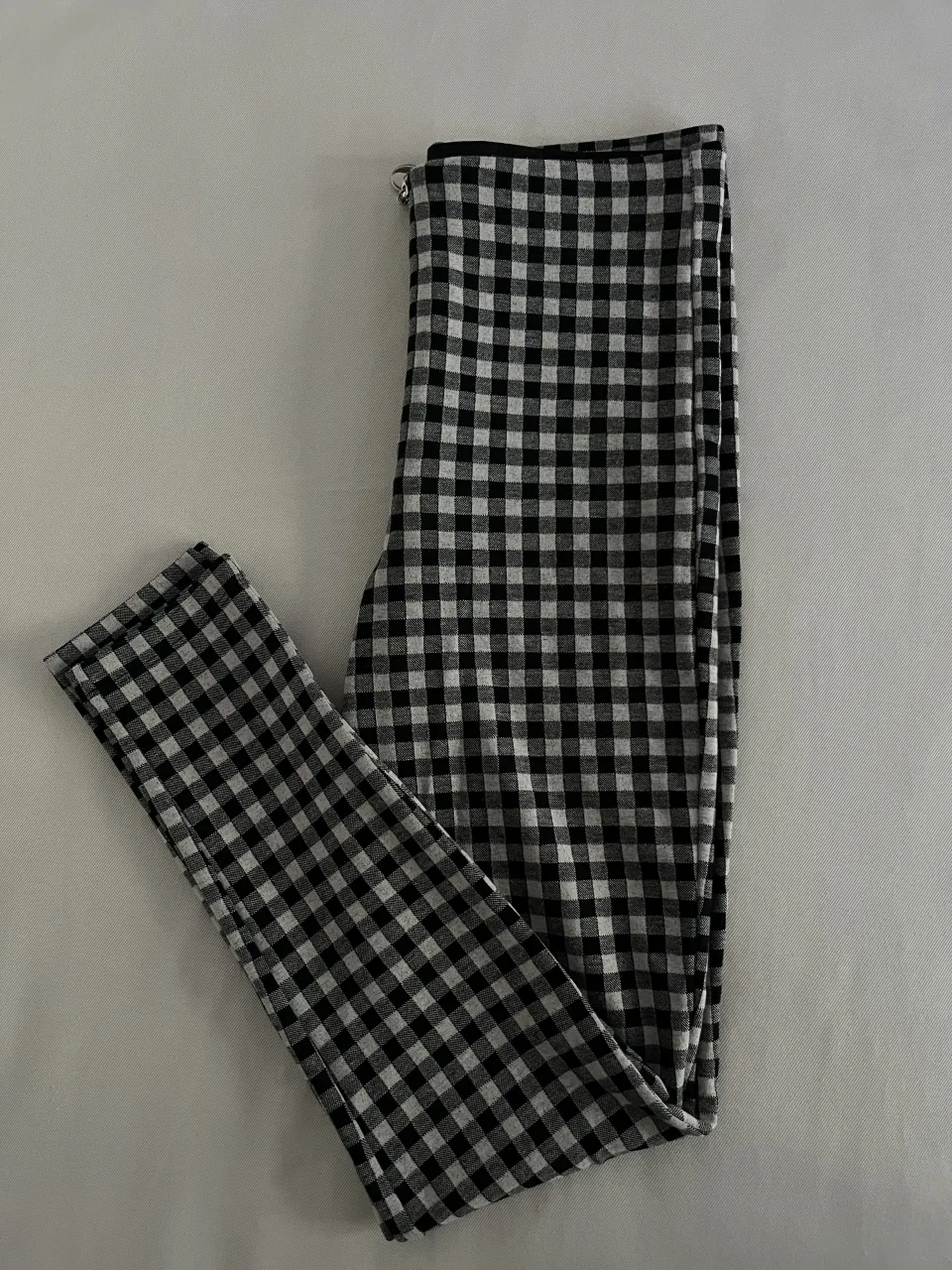 Pantalón de cuadros escoceses en blanco y negro con cierre metálico al frente.