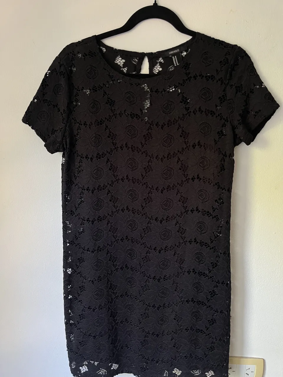 Vestido negro de encaje con mangas cortas y cuello redondo. viene con un vestido negro básico abajo 