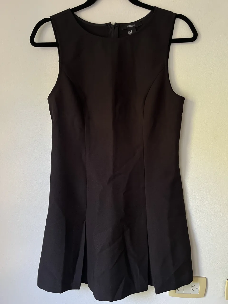 Vestido negro sin mangas con cierre en la espalda y detalles plisados en la falda.