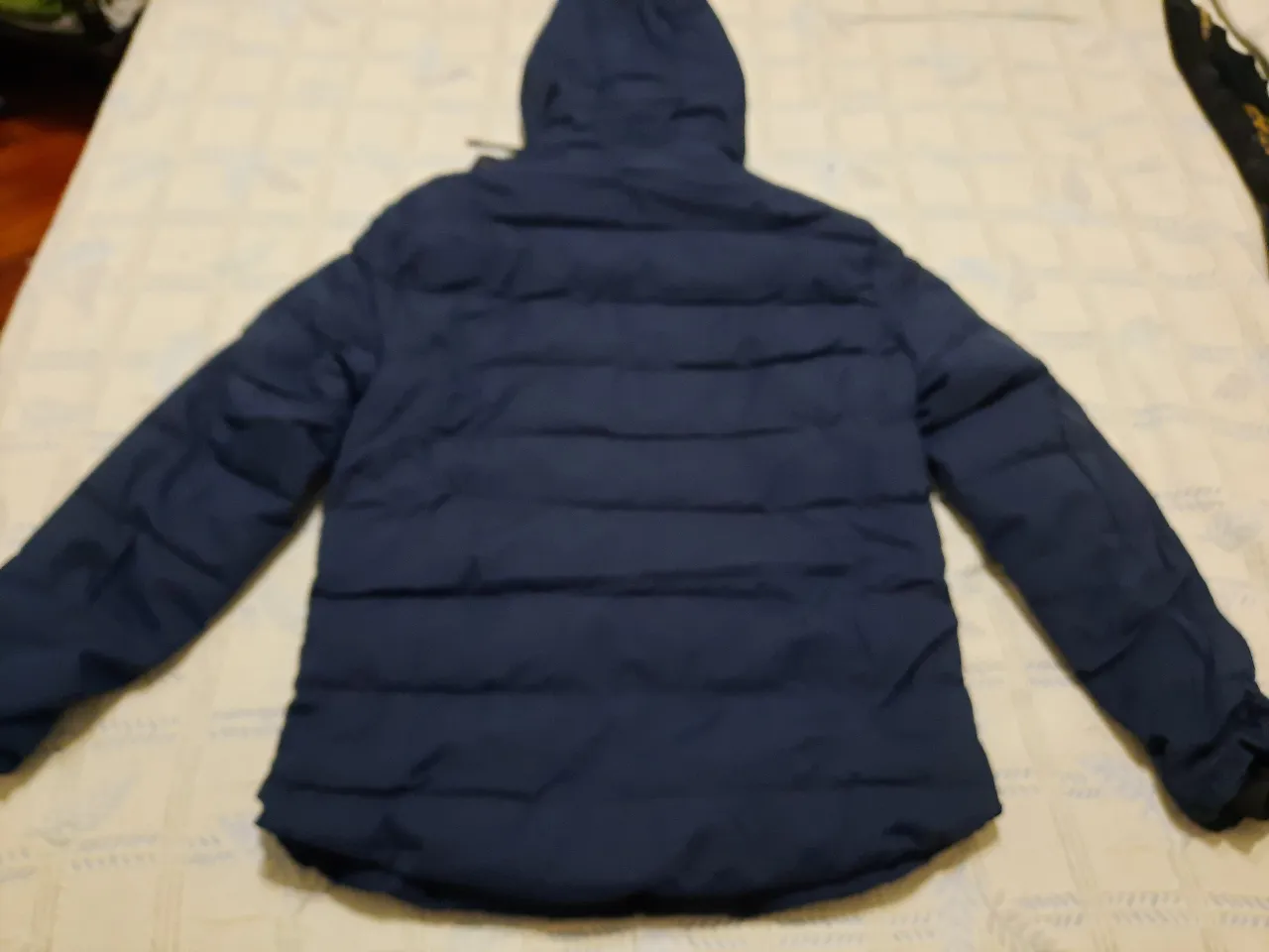 Campera de pluma azul marino con capucha, ideal para el invierno. Cuenta con cierre y bolsillos. Marca Tushidi, talle 7XL.