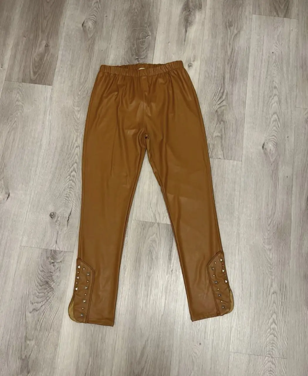 Pantalón de vestir de cuero sintético color marrón con detalles de tachas en los laterales. Talle 2 de la marca Ivana. Ideal para un look moderno y sofisticado.