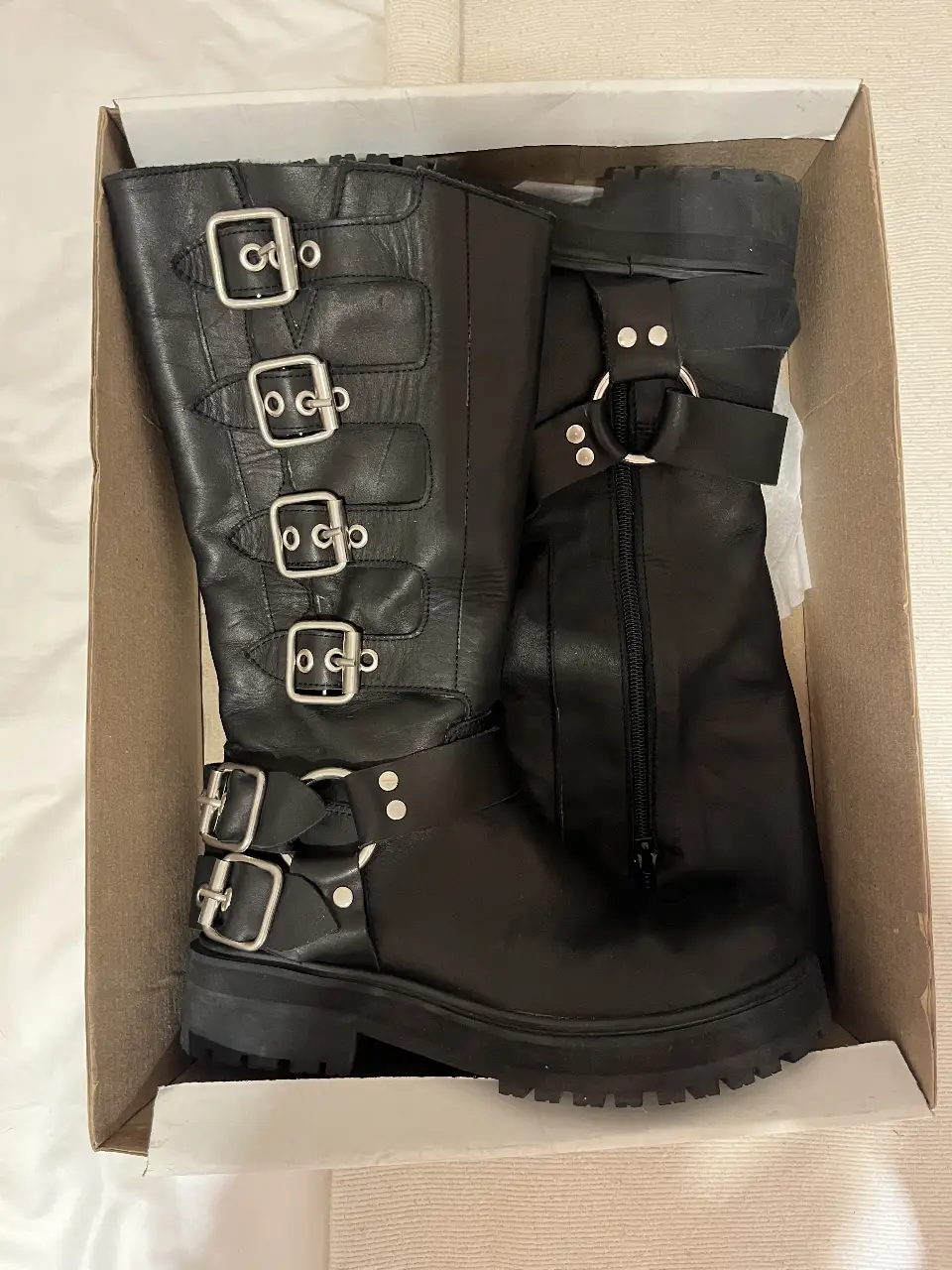 Botas negras de cuero con hebillas y cierre lateral. Estilo rocker y urbano, ideales para un look audaz.