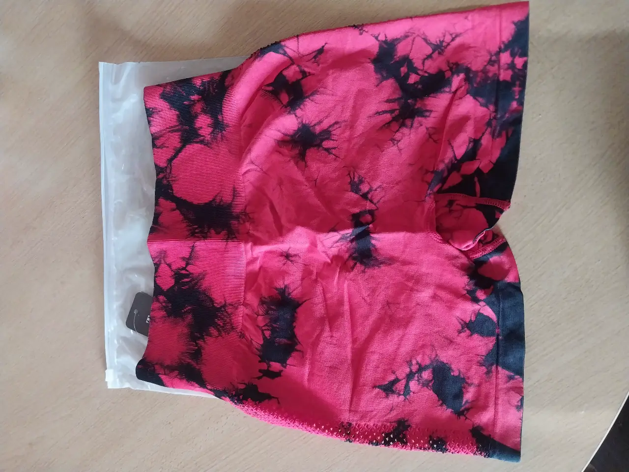 Short deportivo de mujer con estampado tie-dye en tonos rojo y negro. Ideal para entrenamientos y actividades físicas. Diseño moderno y cómodo.