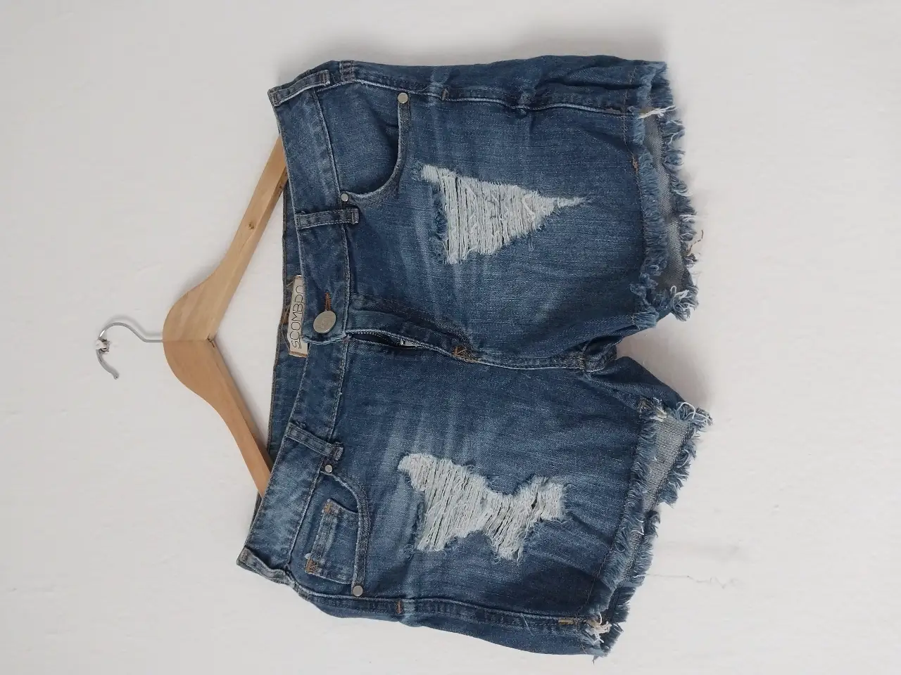 Short de jean azul con roturas y detalles desflecados. Ideal para un look casual y moderno.