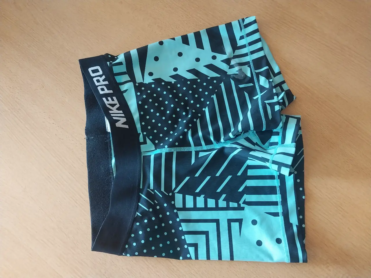Calzas deportivas Nike Pro, con diseño geométrico en tonos negro y celeste. Talle S, ideales para entrenamientos.