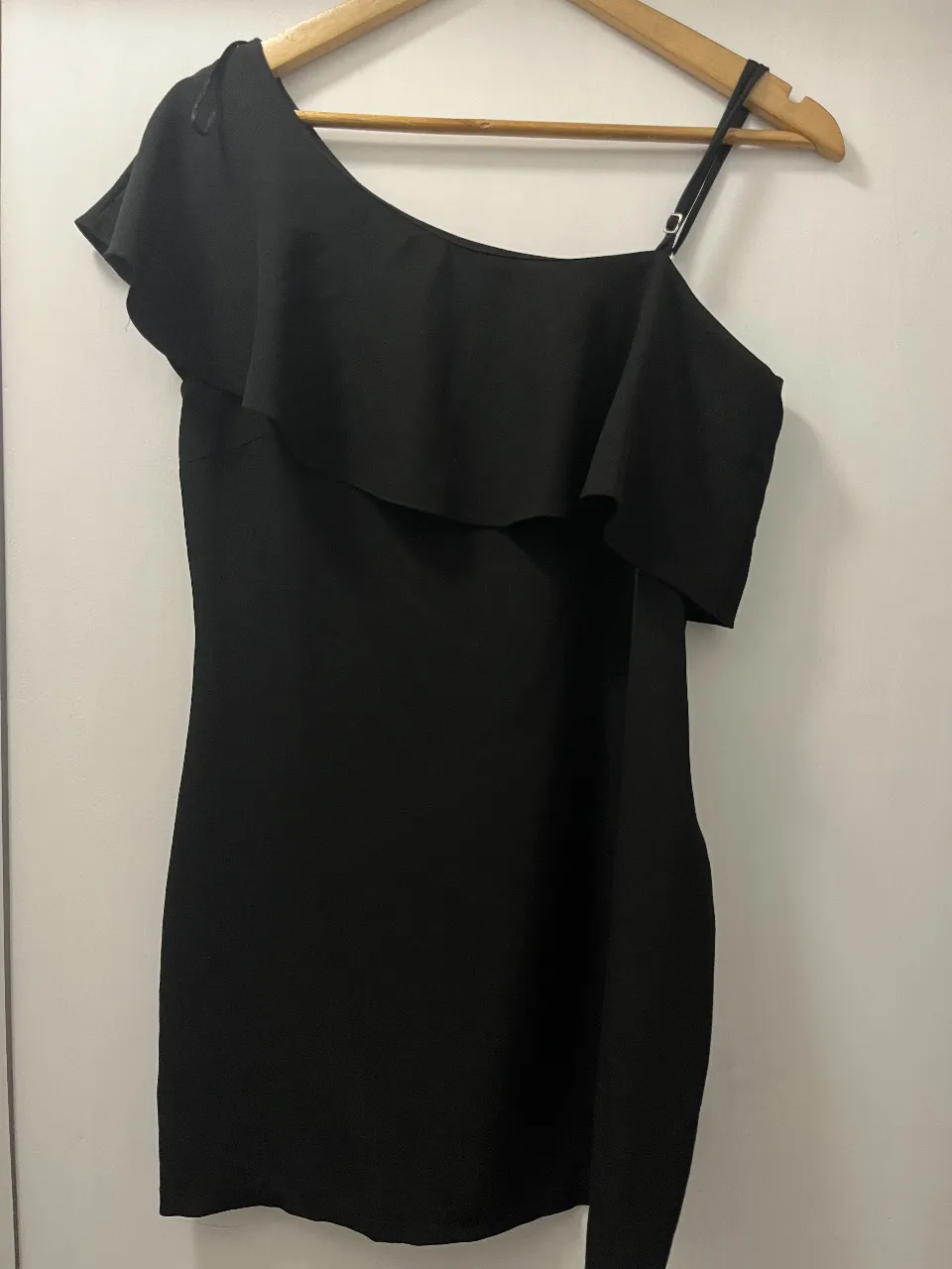 Vestido negro de fiesta, con un solo hombro y volado. Ideal para una salida elegante o una fiesta.
