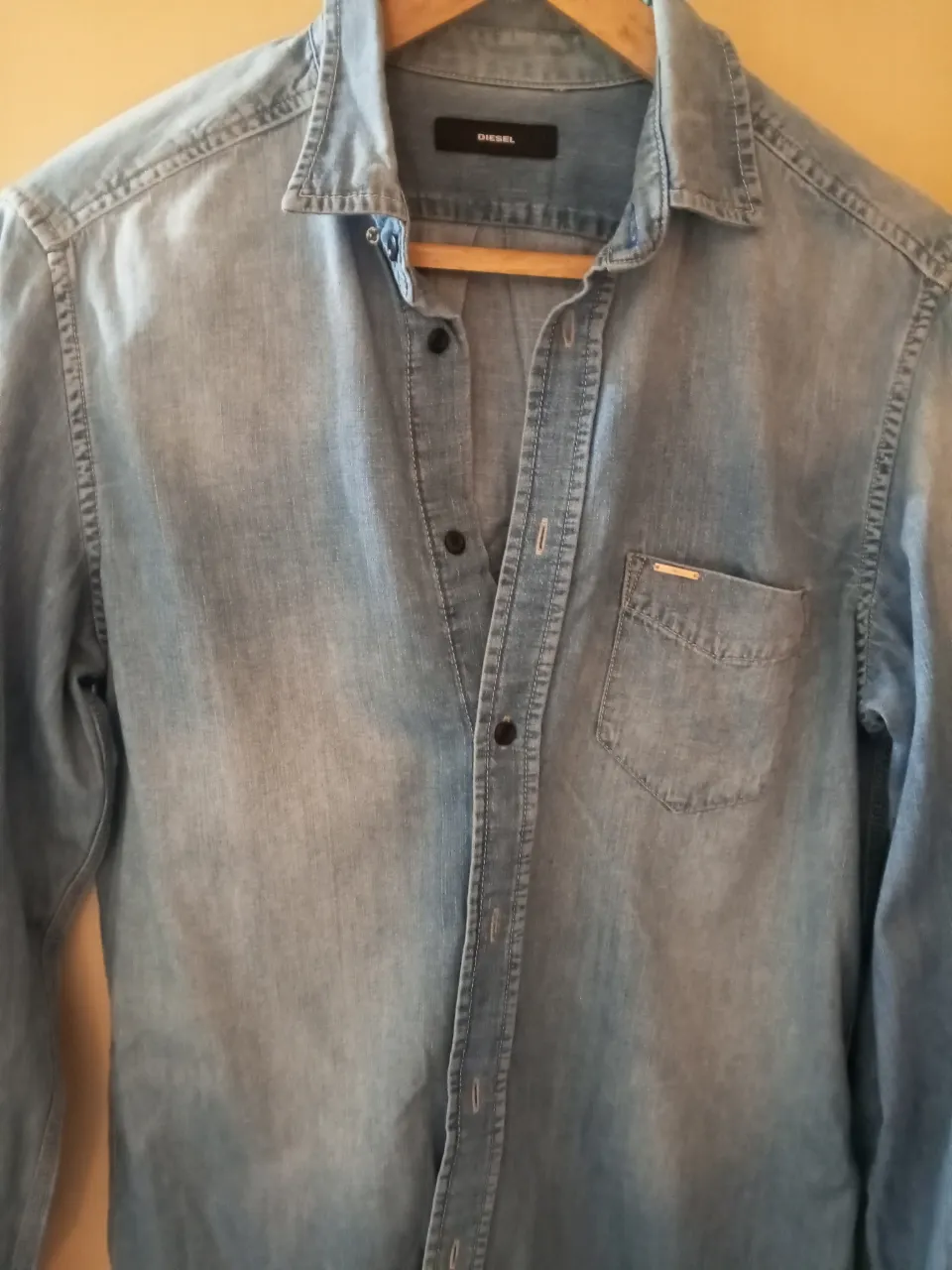 Camisa de jean celeste Diesel, manga larga, con bolsillo en el pecho y etiqueta de la marca. Ideal para un look casual y moderno.