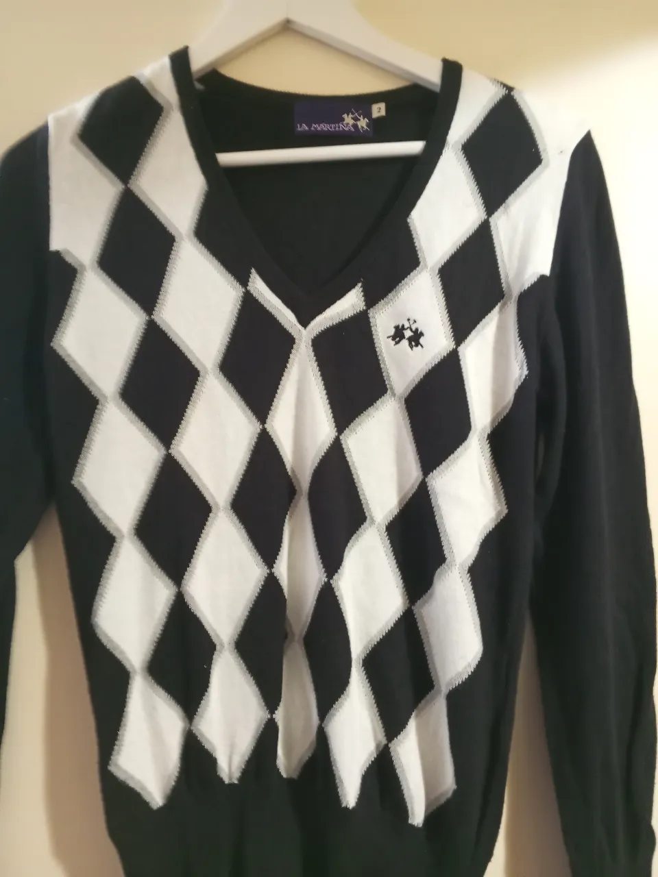 Sweater de hombre con diseño de rombos en blanco y negro, cuello en V. Ideal para un look preppy y elegante.