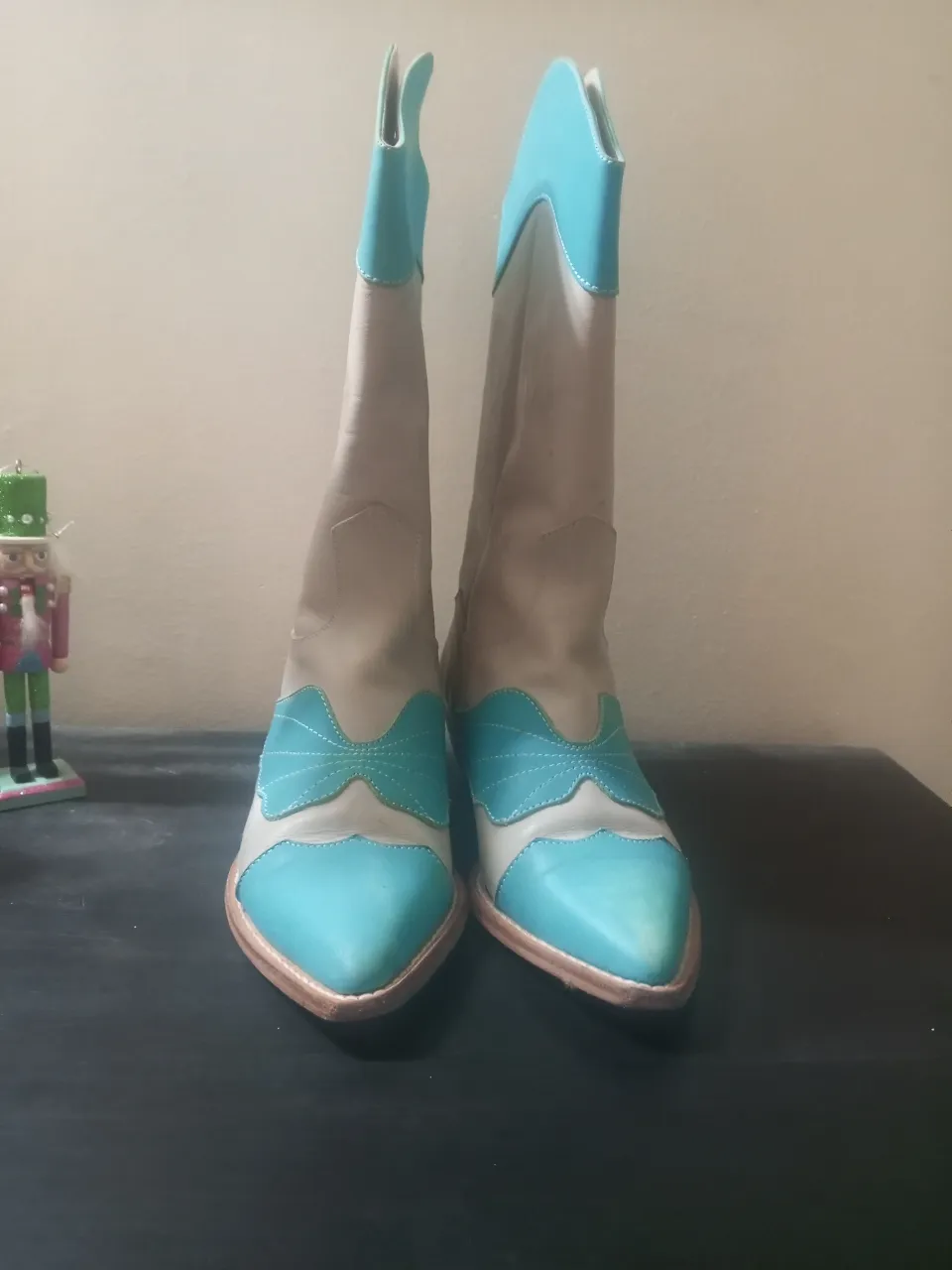Botas de caña alta estilo cowboy en color blanco y celeste. Diseño con detalles en celeste en la puntera, empeine y parte superior de la caña. Ideales para un look moderno y audaz.
