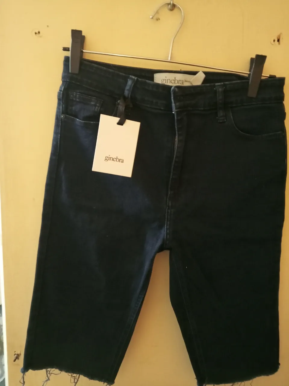 Short de jean negro de mujer, con corte desflecado en el borde inferior. Tiro medio y calce recto. Marca Ginebra.