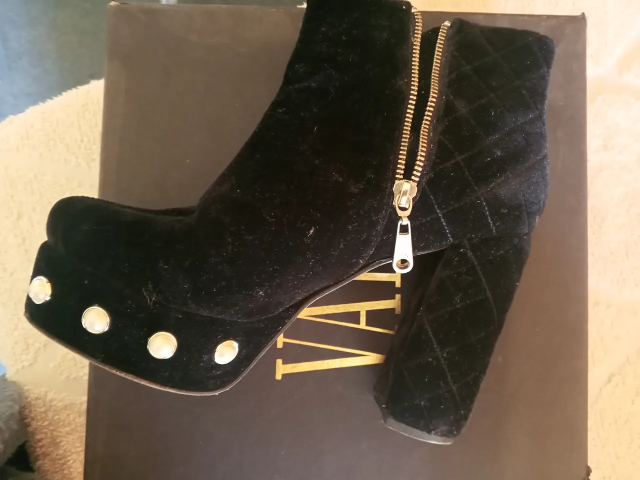 Botines de terciopelo negro con plataforma y taco ancho. Detalles de tachas doradas en la plataforma y cierre dorado lateral. Ideales para un look de fiesta o salida.