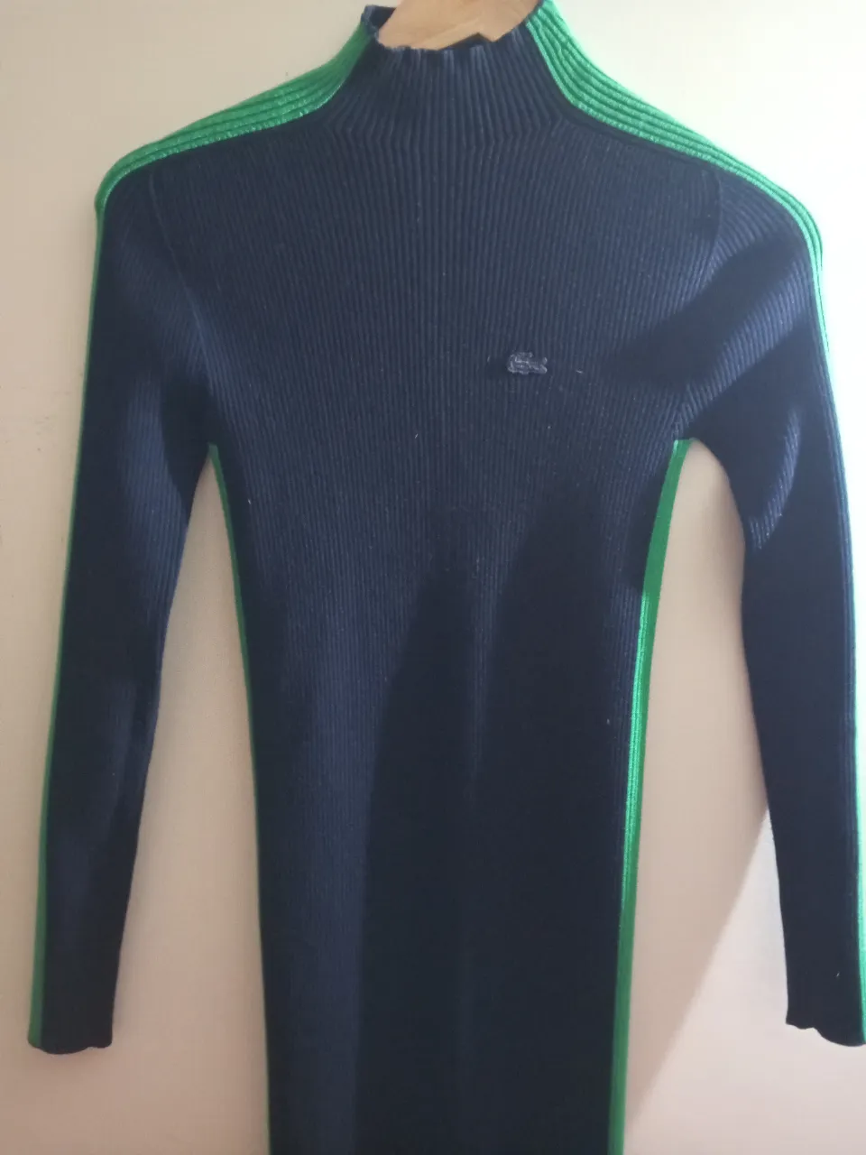 Vestido midi de punto acanalado negro con detalles en verde. Cuello alto y corte entallado, con el logo de la marca bordado. Ideal para un look elegante y moderno.