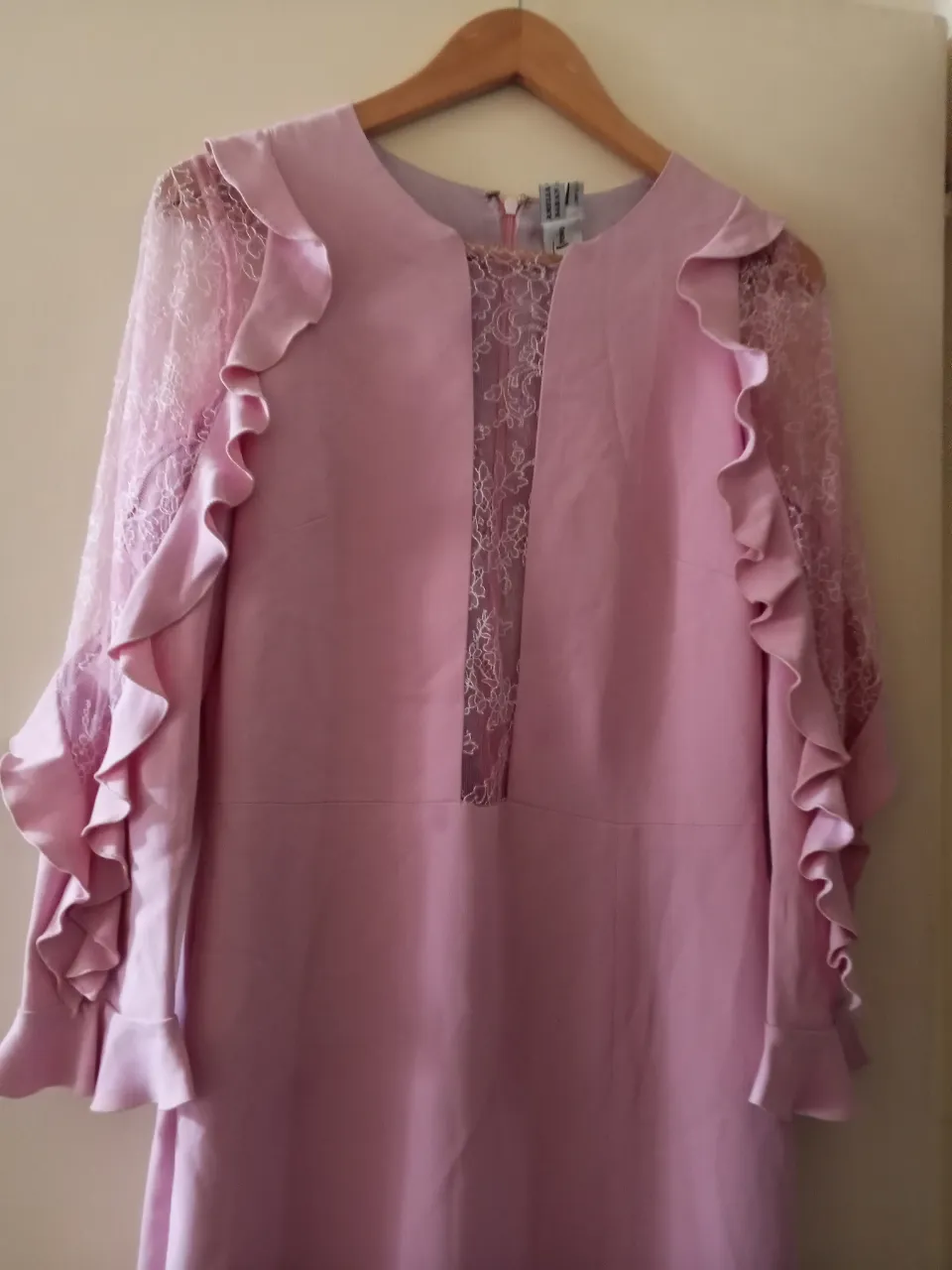 Vestido midi rosa con mangas largas de encaje y volados. Ideal para eventos especiales.