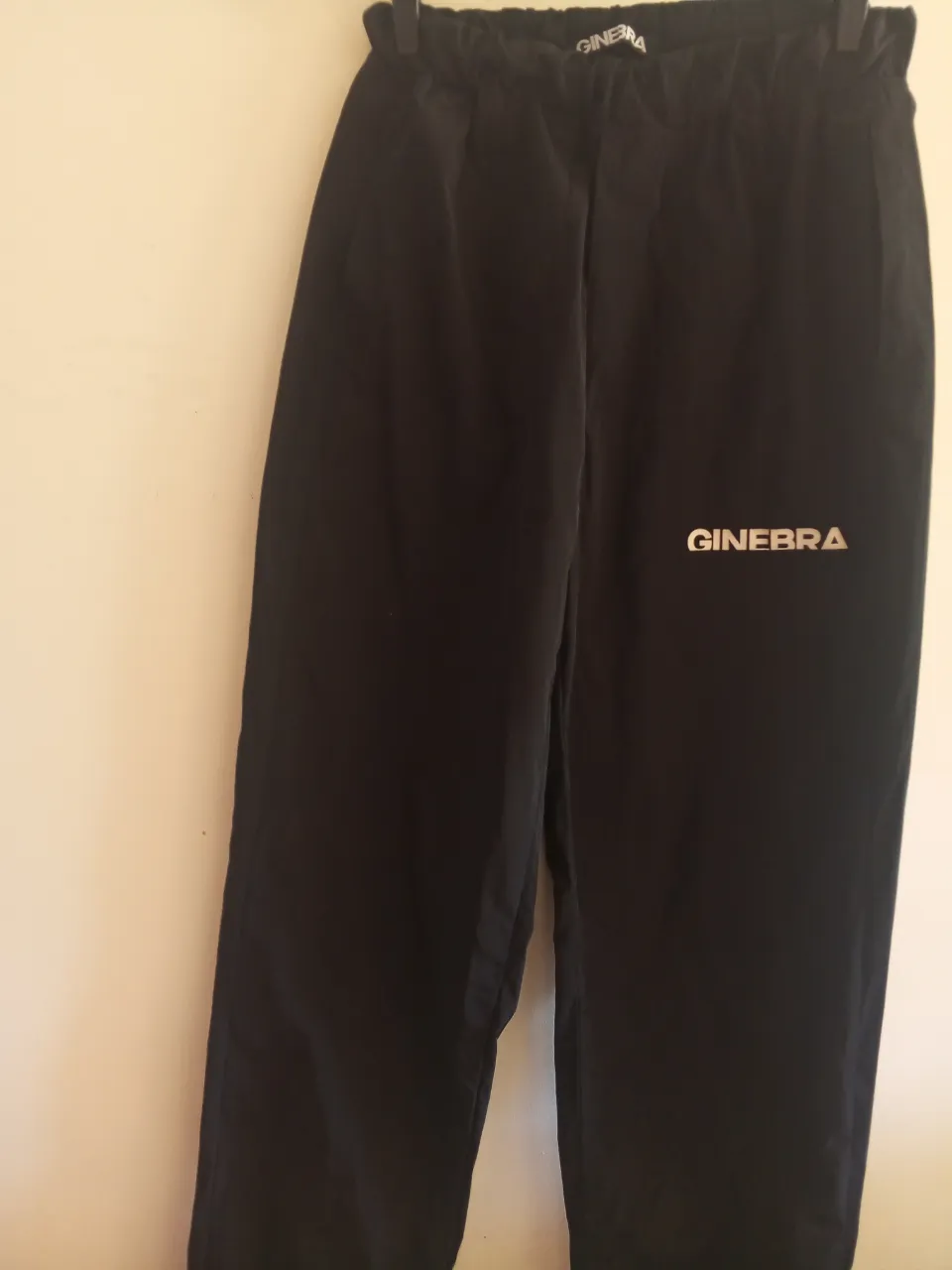 Pantalón deportivo negro de hombre, con el logo GINEBRA en blanco. Ideal para un look casual y cómodo.