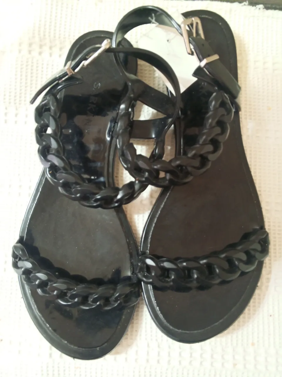 Sandalias negras con detalle de cadena gruesa. Ideales para un look moderno y cómodo.