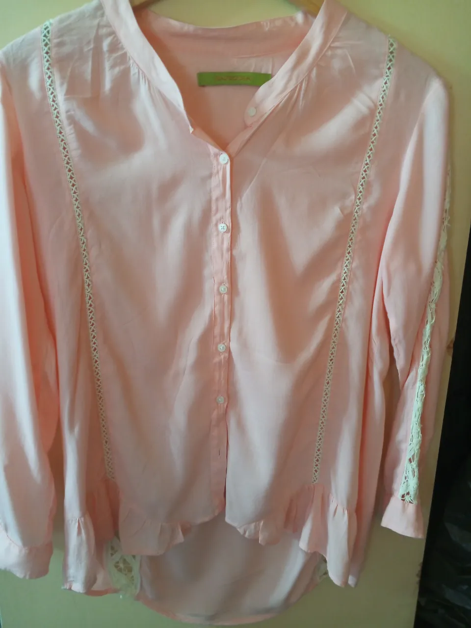 Blusa rosa con detalles de encaje en los laterales y mangas. Cuello mao y botones frontales. Ideal para un look casual y femenino.