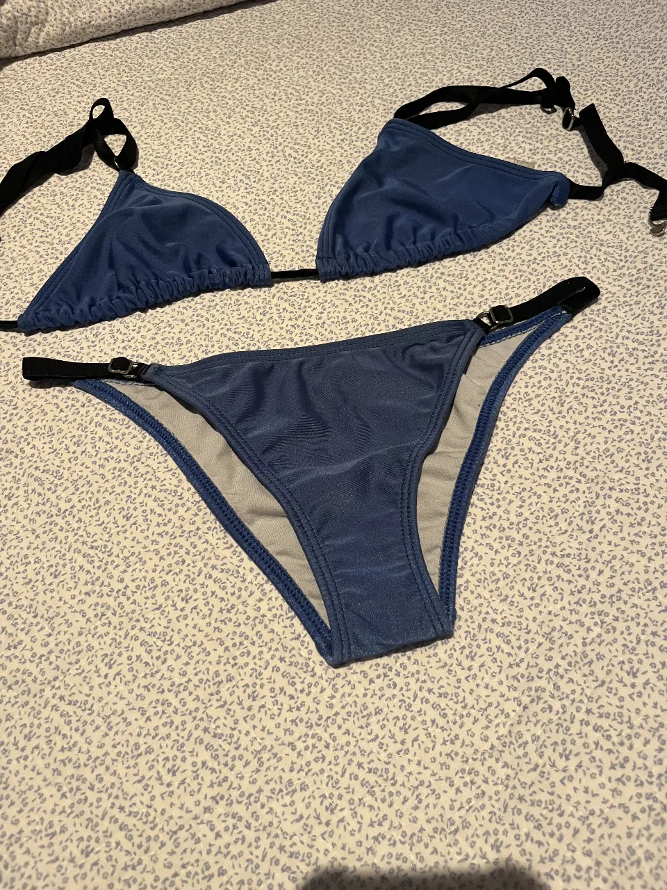 Bikini azul con detalles negros y hebillas plateadas. Ideal para disfrutar del sol y el mar con estilo.