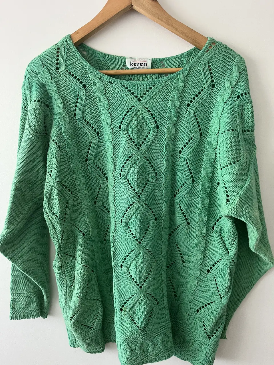 Sweater de punto verde con diseño calado y detalles trenzados. Cuello redondo y mangas amplias. Ideal para un look casual y cómodo.