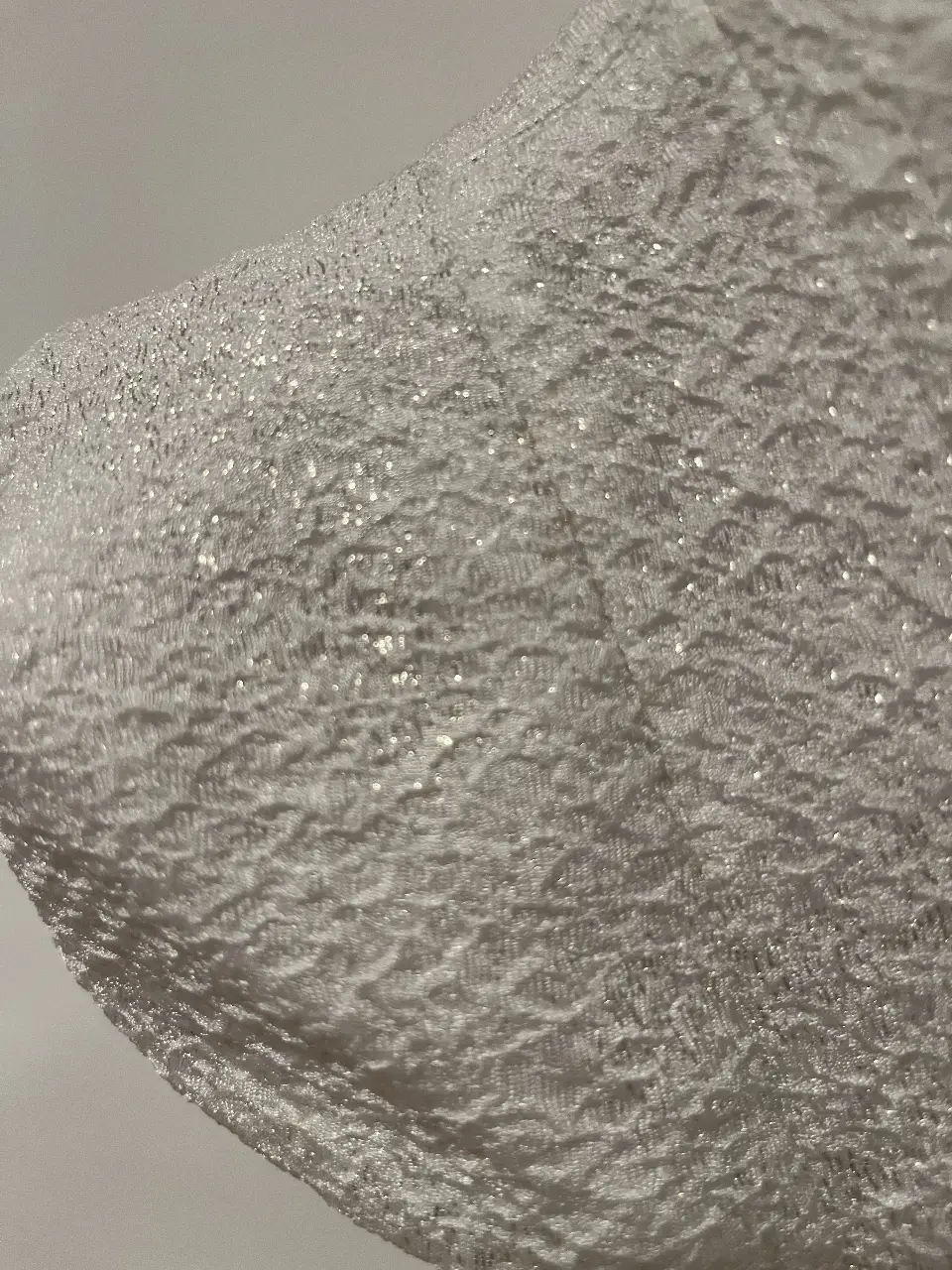 Vestido mini blanco con textura brillante, ideal para fiesta. Diseño con hombros descubiertos y detalles elegantes.