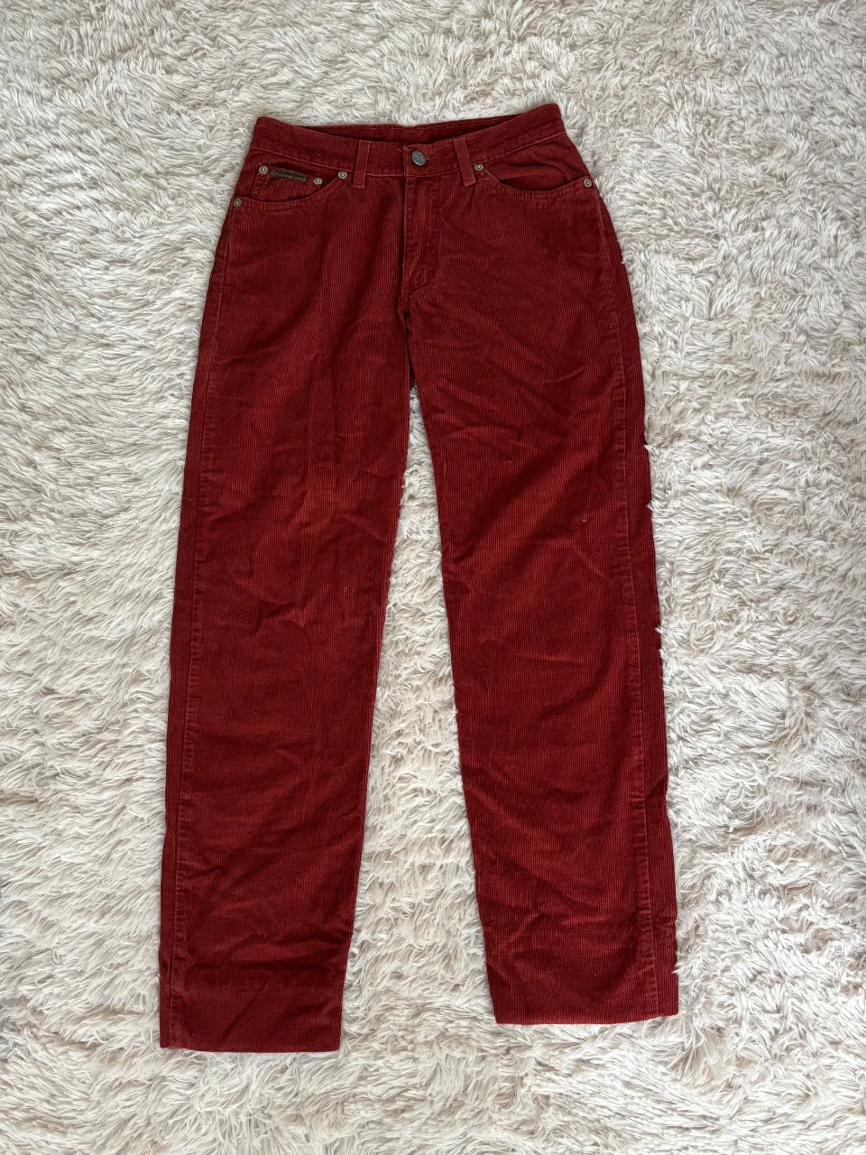 Pantalón de corderoy rojo de la marca Calvin Klein, tiro bajo y corte recto. Posee un dobladillo por el cual se le pueden agregar 7cm de largo.

Medidas

Largo: 93cm (se puede alargar a 100cm)
Ancho: 35