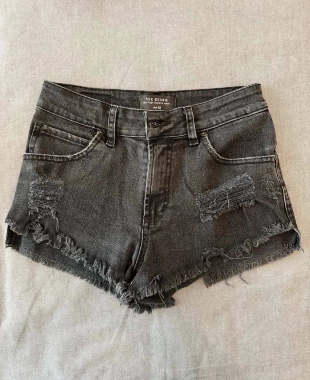Shorts de jean grises con roturas y detalles deshilachados en los bordes.