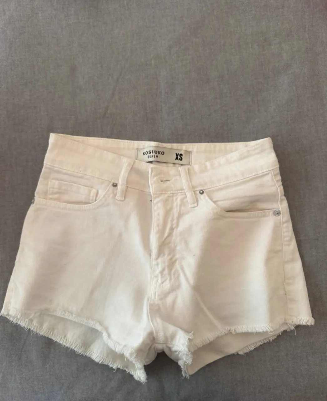 Shorts de jean blancos con roturas y detalles desflecados en los bordes.