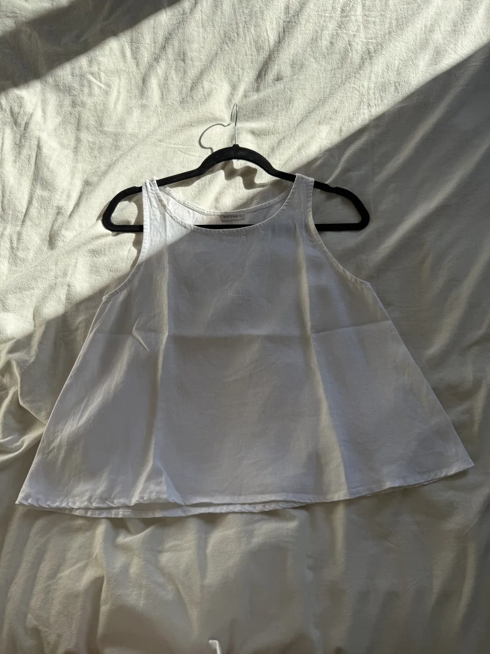 Musculosa blanca de corte amplio, ideal para los días de calor. Su diseño simple y fresco la hace perfecta para combinar con shorts o jeans.