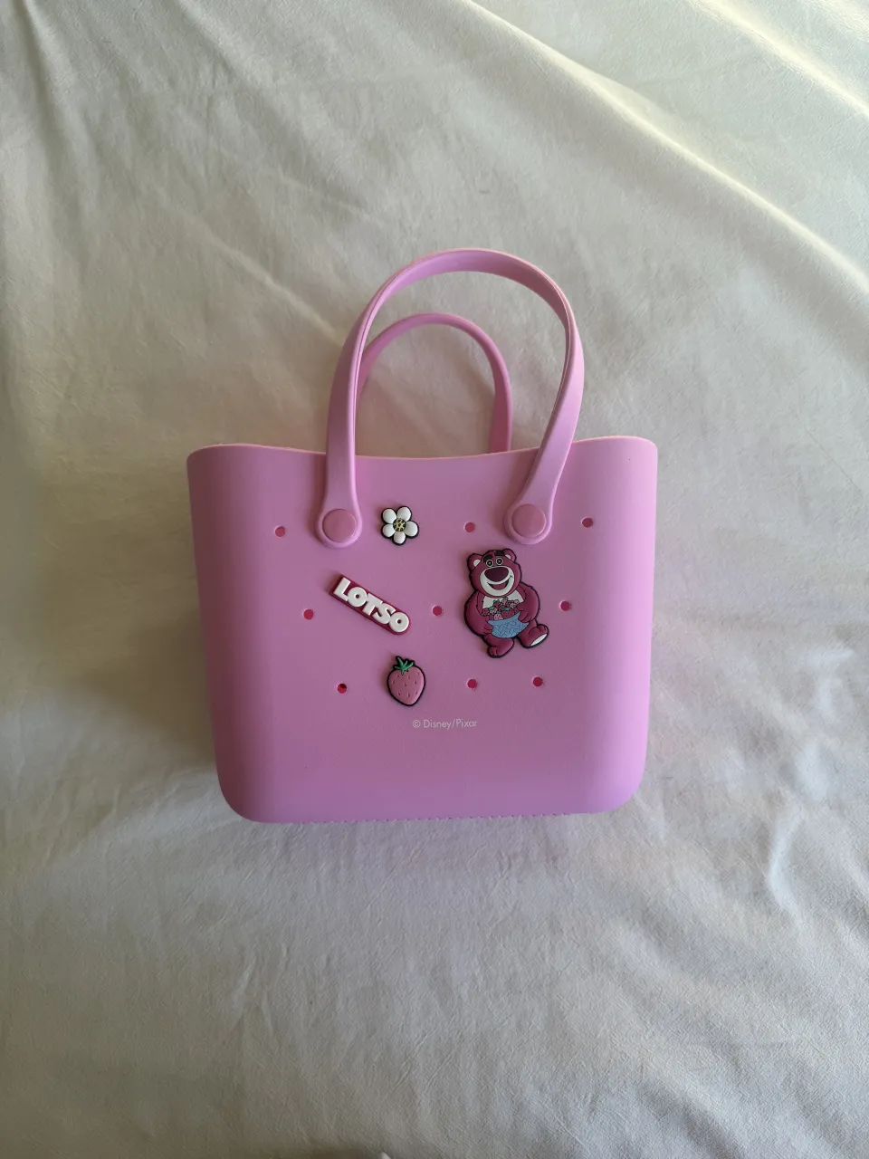 ¡Bolsito súper tierno y práctico! Ideal para las nenas o para llevar lo esencial. Tiene un diseño divertido con apliques de Lotso de Toy Story, una fresita y una flor. Perfecto para el verano, la playa o simplemente para darle un toque canchero a cualquier look.