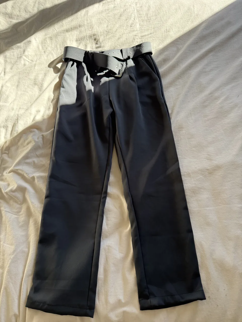 Pantalón gris tiro alto con cinturón y elástico en la cintura. Diseño moderno y cómodo, ideal para un look casual o de trabajo.