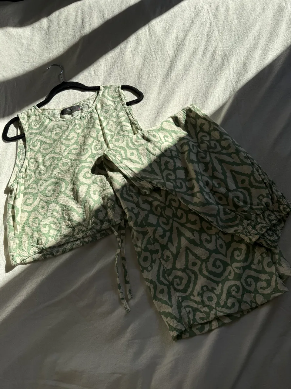 Conjunto de pantalón y top estampado en tonos verdes y crudo. El top es sin mangas y el pantalón tiene cintura elastizada y cordón. Ideal para un look relajado y fresco.