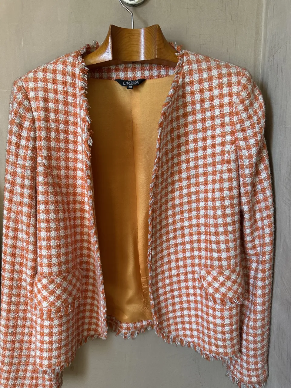 Saco estilo Jackie de cuadros escoceses en naranja y blanco, con un diseño clásico y detalles desflecados en puños y cuello. Ideal para un look canchero y moderno.