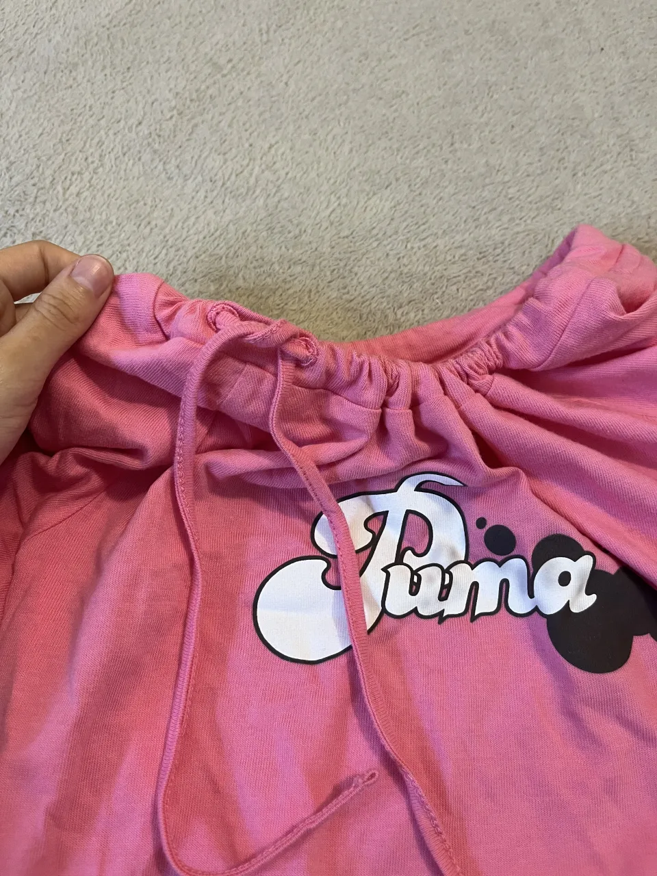 Remera manga corta de color rosa con estampa de la marca "Puma" en el frente. Posee cordón ajustable en el cuello.