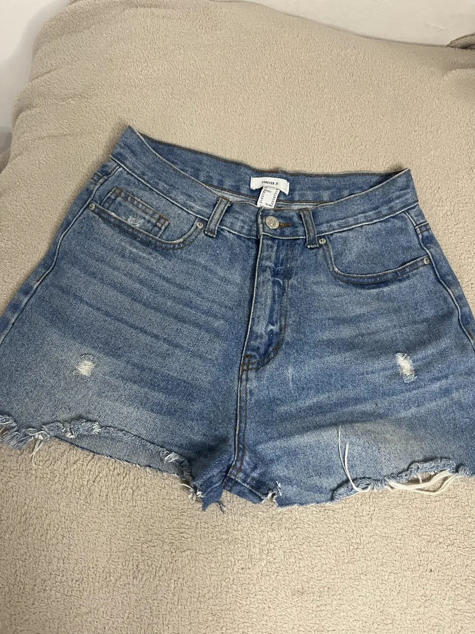 Shorts de jean tiro alto con roturas y ruedo deshilachado. Cierre con botón y cierre.