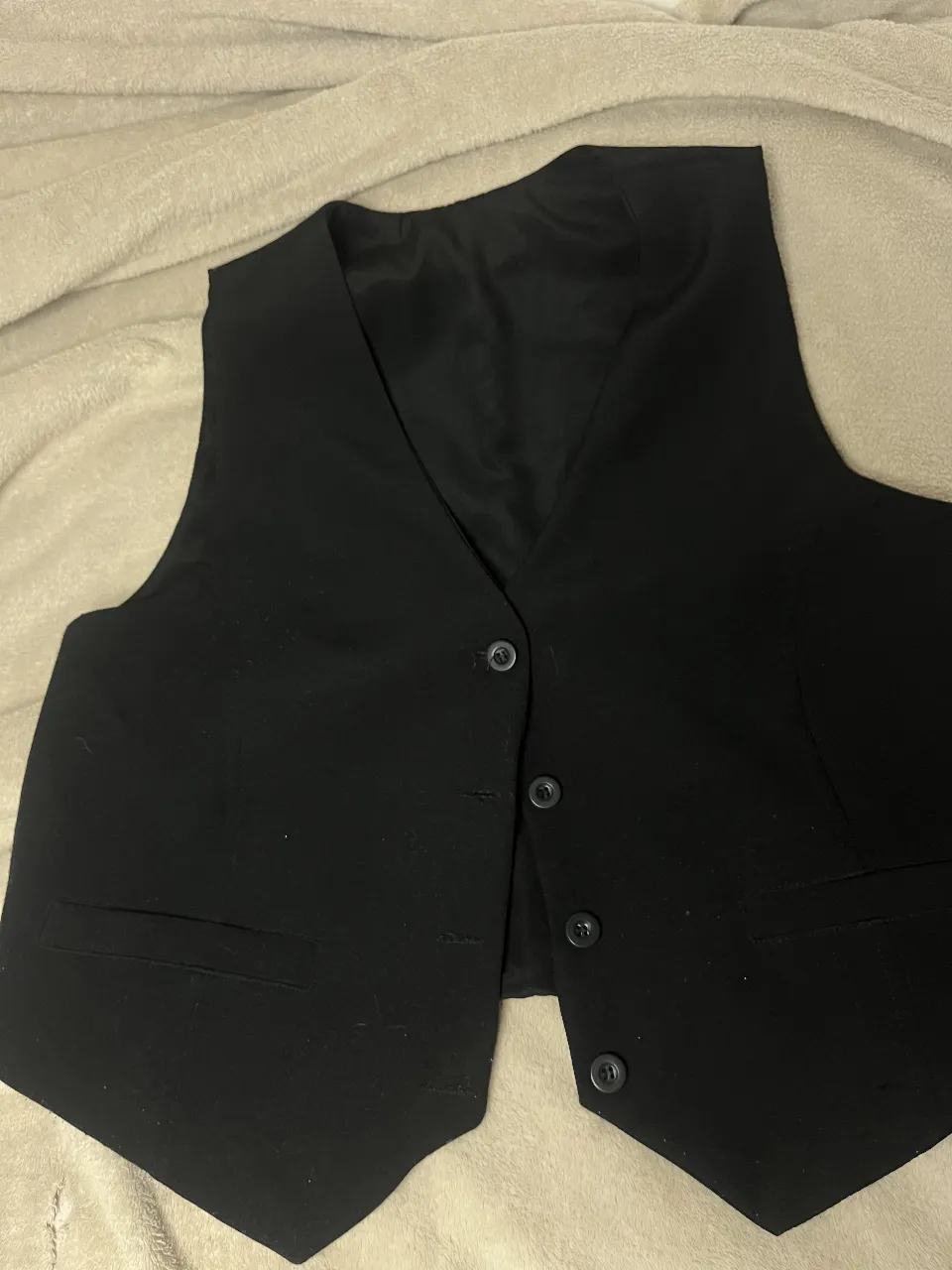 Chaleco de vestir negro, ideal para complementar un traje o para un look más formal. Posee botones al frente y bolsillos laterales.