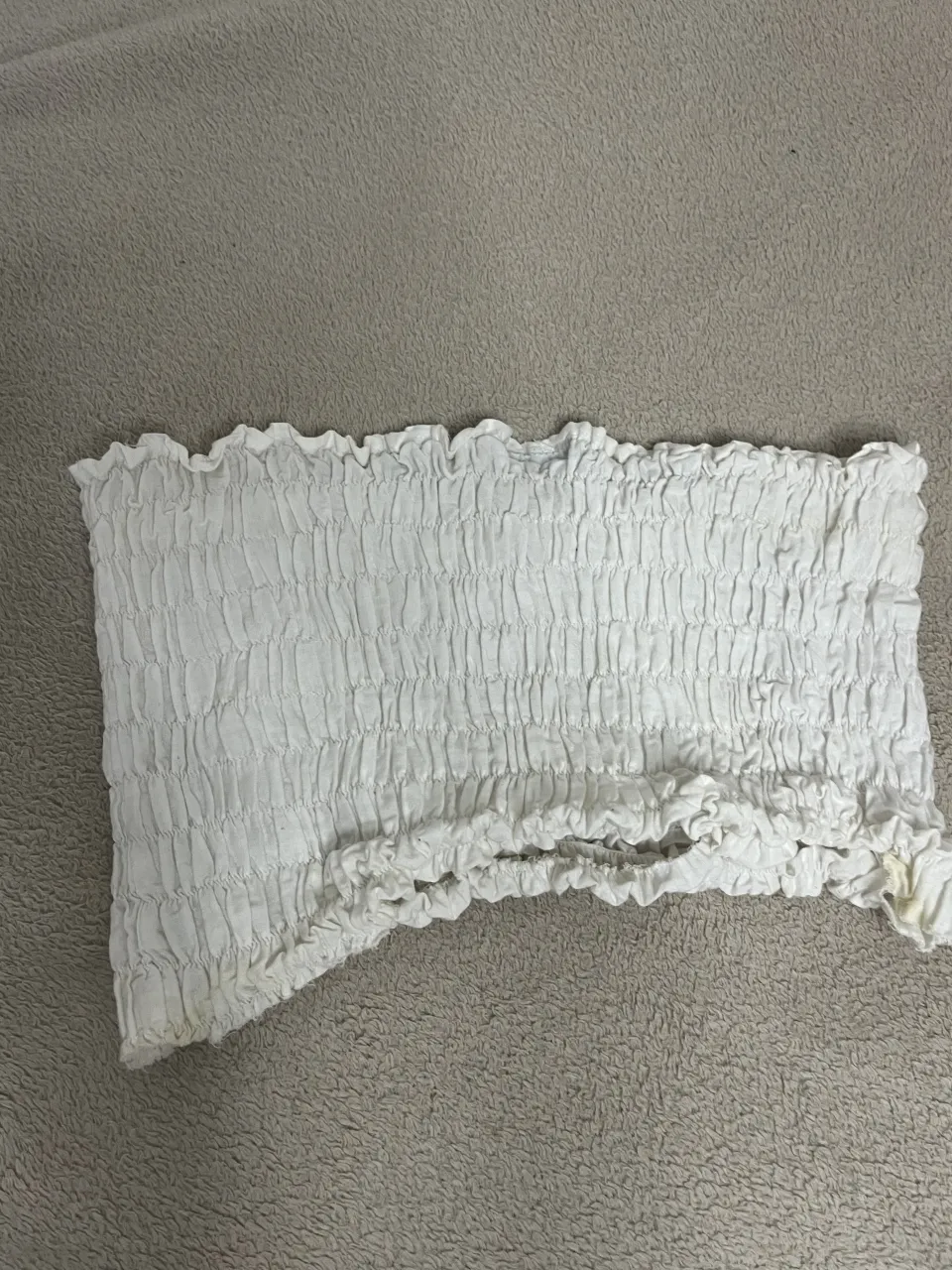 Top strapless blanco de tela fruncida con volados en los bordes.