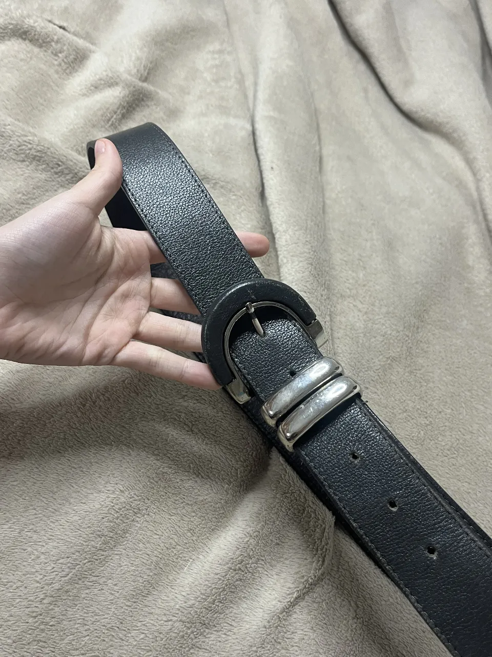 Cinturón de cuero negro con hebilla metálica plateada. Un accesorio clásico y versátil para complementar cualquier outfit.