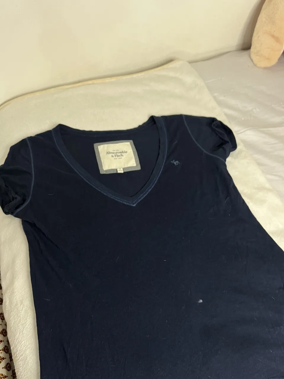 Remera azul marino de manga corta con escote en V. Tiene un pequeño bordado de un alce en el frente. Ideal para el día a día.