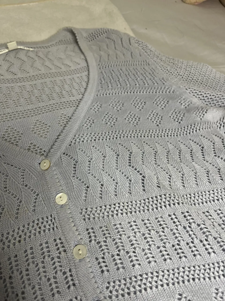 Cardigan de hilo tejido con botones al frente. Diseño calado con rombos y líneas.