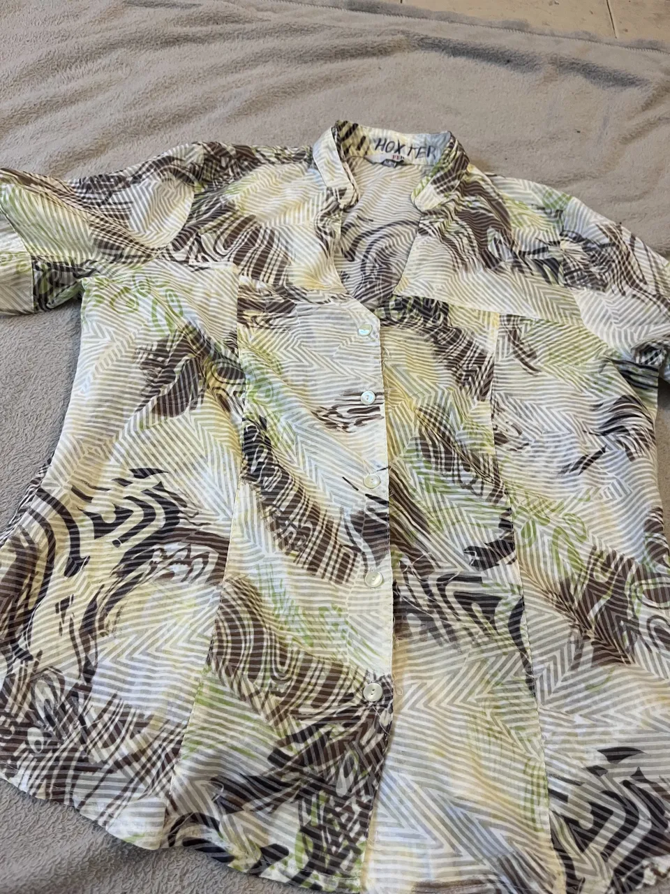 Camisa importada estampada con cuello mao y botones al frente. Posee un estampado abstracto en tonos verdes, marrones y blancos.