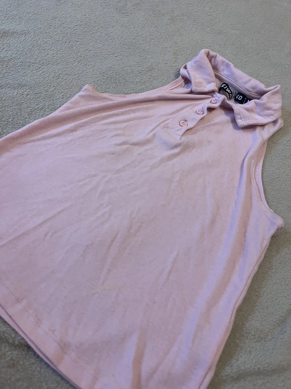 Musculosa rosa con cuello tipo polo y botones al frente.