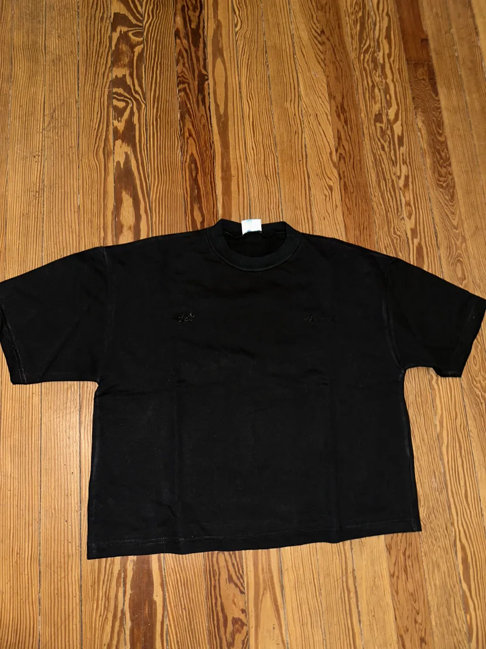 Remera negra boxy-fit con bordado de dos estrellas y el nombre de la marca "Bruder Inc."